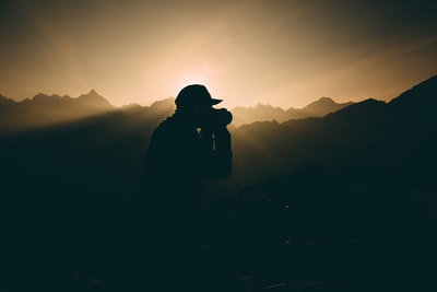 轮廓的人带着相机在落日山脉附近

